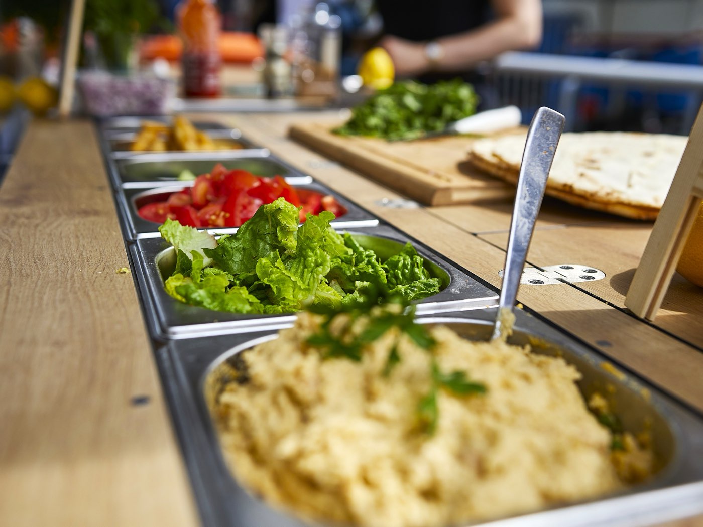 Frische Zutaten am Food-Bike: Salat, Tomaten, Hummus und Fladenbrot